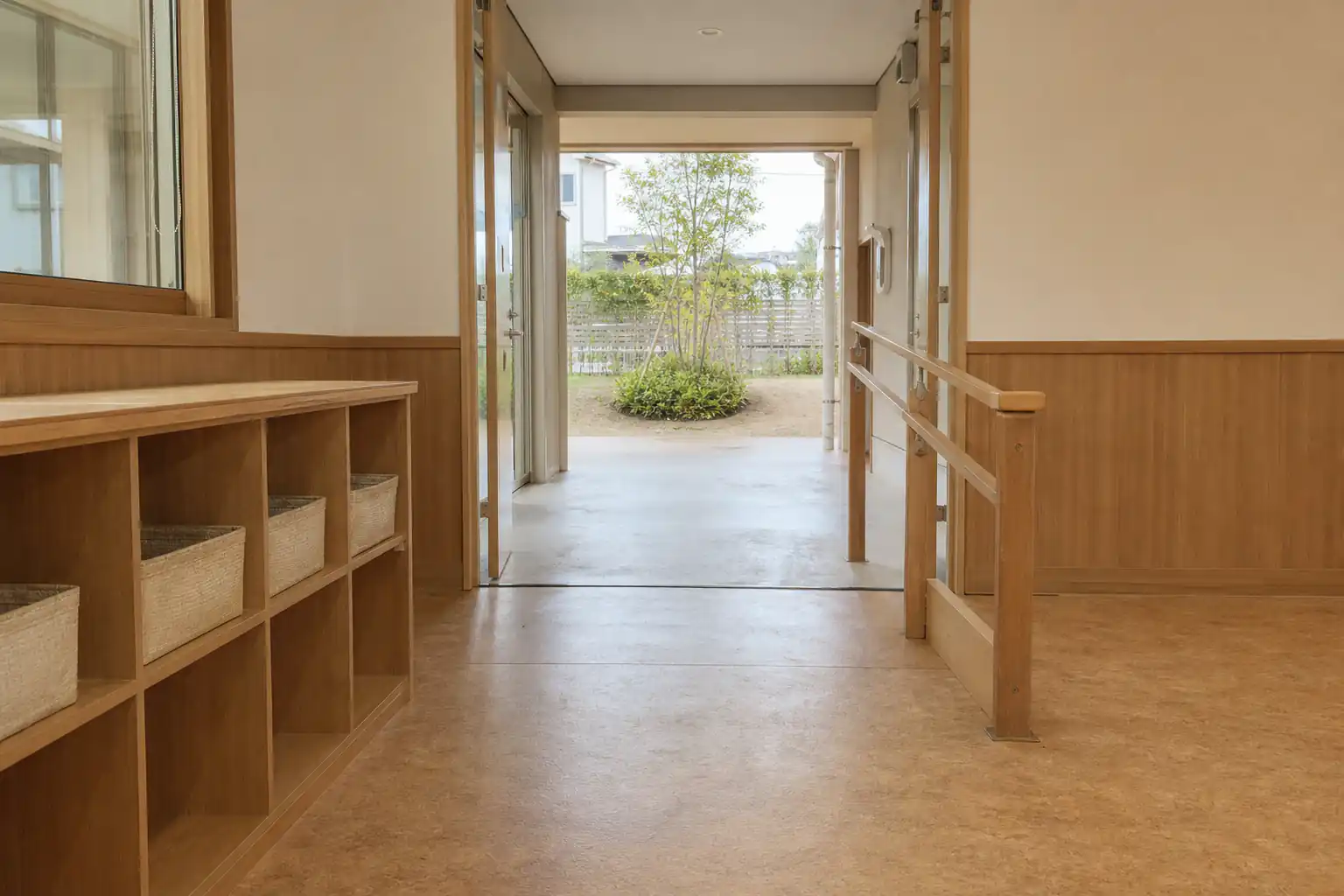 保育室から小さな園庭へ続く、自然光の入る低い目線の通路