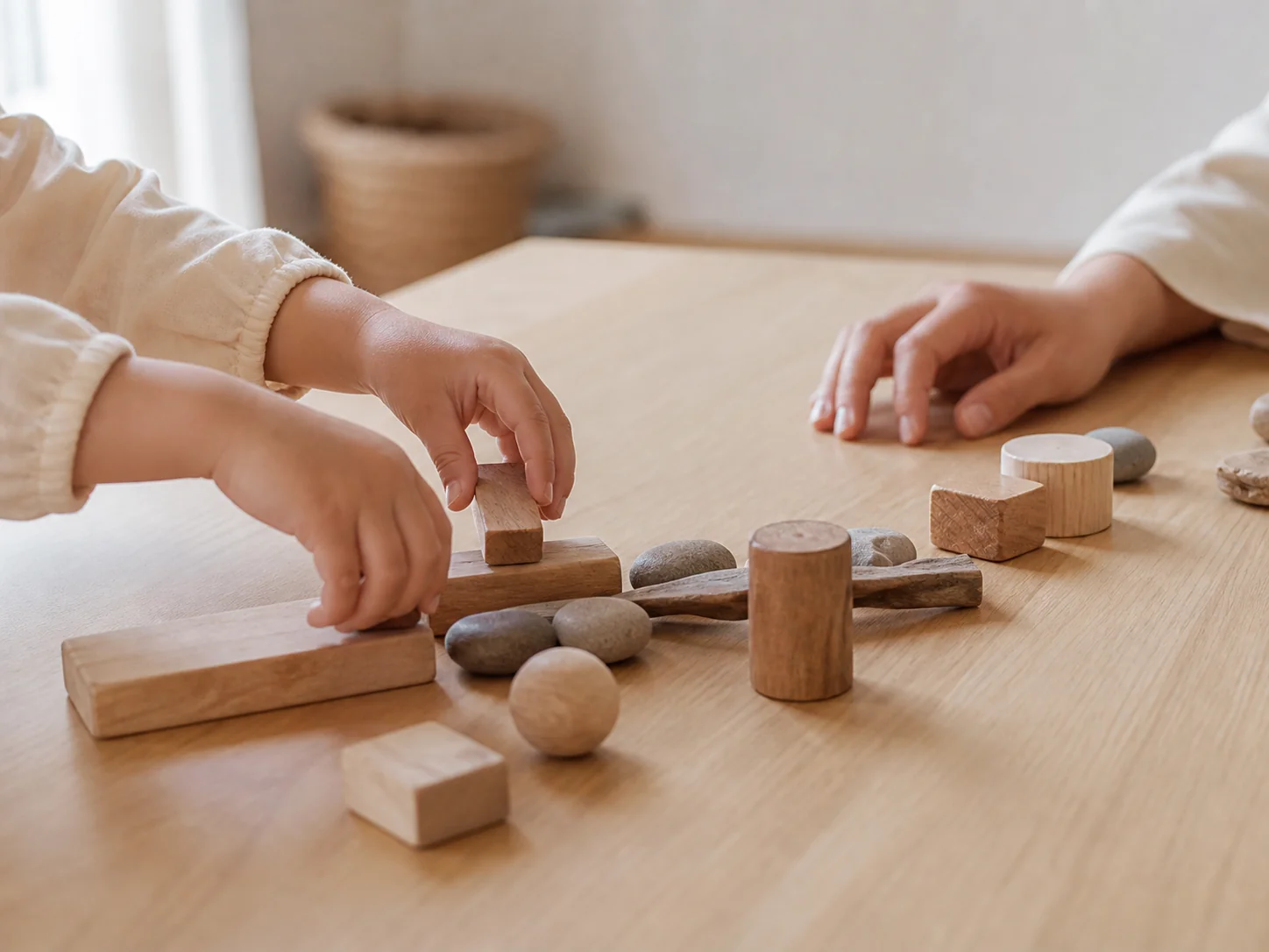 顔を写さず、木片と石をゆっくり並べる子どもと保育者の手元